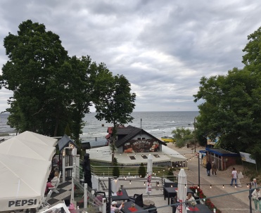 Widok na plażę z promenady w Rewalu, z ludźmi spacerującym