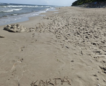 Napis "Karta Rewal" na piasku na plaży.